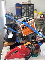 Photo showing the red Husqvarna power tool handle, hardware drawers, and the bench grinder secured with blue straps.