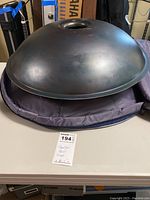 Top view of brass-colored handpan drum resting on open padded case