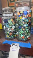 Front view of round and octagonal glass jars filled with assorted marbles.