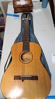 Top view of Kay classical acoustic guitar lying in blue soft case on table