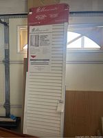 Two prefinished white full louver bi-fold doors shown vertically, packaged in original Masonite box with product label visible indicating size and features.