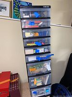 Full view of the eight-drawer black plastic mini chest filled with office supplies and taped shut with blue painter's tape.
