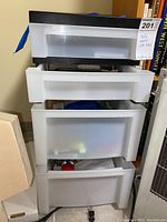 Photo of stacked three white plastic drawers with semi-transparent fronts and black top, showing overall storage bin.