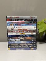 Stack of 15 DVD movies showing visible titles on spines including Down to You, The Number 23, Charlie and the Chocolate Factory, and others.