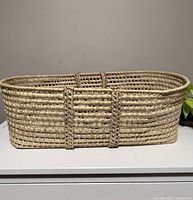 Front view of large vintage wicker basket/bassinet showing rectangular shape and woven structure with integrated handles.
