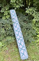 Rolled view of the blue and white outdoor patio rug, showing the geometric pattern and woven texture.