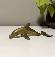 Side view of vintage brass dolphin figurine showing profile and finish