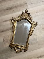 Full view of the mirror showing the overall shape, size, and ornate frame design.