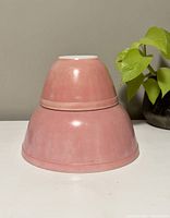 Two pink vintage Pyrex mixing bowls stacked inverted, showing outer pink color