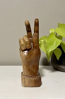 Front view of vintage wooden hand sculpture showing peace sign gesture with two fingers raised.