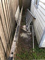 Two ladders leaning against side of building, one 10 ft step ladder and one 16 ft extension ladder, visible weathering and dirt