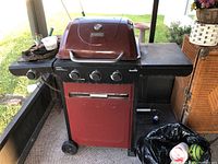 Full view of the red Char-Broil hybrid grill showing three burners, side shelves, and storage compartment underneath.