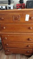 Full view of Virginia House wooden dresser showing multiple drawers and carved leaf detail on top drawer.