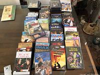 Photo of over fifty DVDs arranged on a table showing a wide variety of titles in multiple genres including family and action movies.