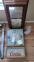 Framed vintage rectangular clock with fishing image leaning against wall near other clock and wrapped cords.