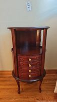 Front view showing 4 carved drawers with brass knobs and open display area above.