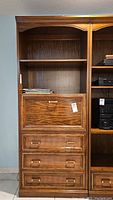 Full view of wood cabinet showing open shelving on top, drop-front compartment, and three cane front drawers below.