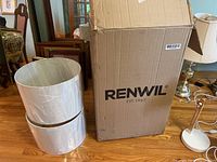 Two white cylindrical lampshades stacked, one in protective plastic, beside RENWIL branded cardboard box