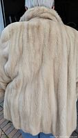 Back view of blond mink coat on model showing full length and fit