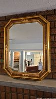 Full view of the octagonal wood framed mirror mounted on a brick wall.