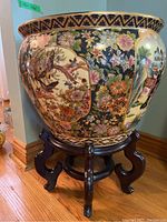 Overall view of ceramic planter seated on wood stand in room corner