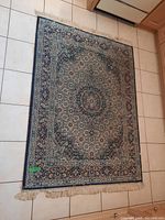 Full view of the rectangular rug laid on tile flooring showing the overall pattern, border, and fringes.