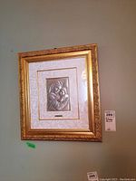 Framed silver relief artwork of Madonna holding child in decorative gold ornate frame with white mat backing, hanging on a wall.