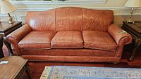 Front view of three-seat brown leather sofa on hardwood floor