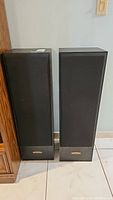 Two black Pioneer tower speakers side by side with fabric front covers and wood-like bases.
