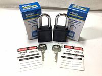 Photo showing two black Brady nylon lockout padlocks with steel shackles, each accompanied by a pair of keys and a laminated safety tag.
