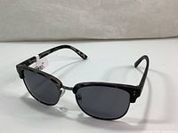 Side angled view showing tortoiseshell patterned frame on the arms, dark polarized lenses and metal bridge.