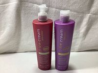 Front view of two 300 ml hair care bottles, one red (conditioner) and one purple (shampoo) showing branding and product details.