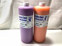 Photo showing two large 1 litre bottles of Children's Choice tempera poster paint, magenta and orange colors, with labels visible.