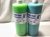 Photo showing two large 1 litre bottles of Children's Choice tempera poster paint in green and turquoise colors, with clear labels and white caps.