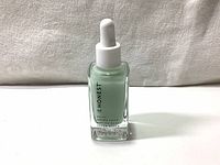 Front view of a 30ml glass bottle containing a green serum with a white dropper cap, label shows 'HONEST Daily Green Juice Antioxidant Super Serum'.