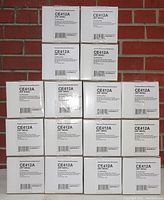 16 white boxes of HP CE412A (305A) yellow toner cartridges by NuPrint, stacked in a pyramid formation showing the product labels clearly.