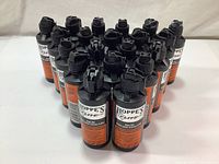 Twenty black bottles of Hoppe's Elite Gun Oil arranged together, showing label and bottle design.