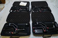 Set of four Hohem gimbal stabilizers in open black protective carrying cases, all batteries missing, one case missing battery charger.
