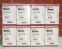 Photo of eight white boxes of RAM remanufactured toner cartridges RAM1415B CE320A stacked in two rows of four against a brick background.