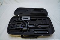 Open black hard shell case with Zhiyun Crane 2 gimbal stabilizer inside foam insert compartments showing handle, motor arms, and lens mounting plate