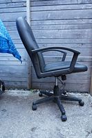 Side view of black leather office chair showing cushioned seat, armrest, wheels, and adjustable height lever