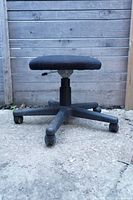 Side view showing the low-height padded seat covered in dark fabric and five-wheel base.