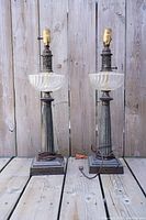 Front view of two vintage lamps with glass bodies and metal stands, showing overall condition and missing shades.