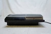Side profile view of Sony PlayStation 3 console in black with slots and buttons visible