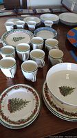 Christmas-themed plates, bowls, and matching mugs showing Christmas tree and wreath designs