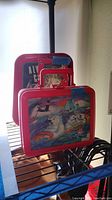 Photo shows side view of the Coca Cola metal lunch box with colorful polar bear winter scene and thermos behind it.