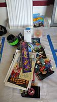 Wide view of various Disney collectible items spread on a surface including pins, buttons, toys and promotional papers.