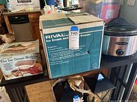 Photo of Rival ice cream maker box with packaging and kitchen background including Hamilton Beach crockpot and another boxed ice cream maker.