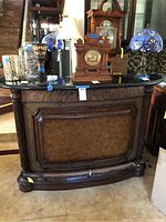 Front view of Tommy Bahama bar showing zebra wood finish and marble top with decorative details and cabinetry.