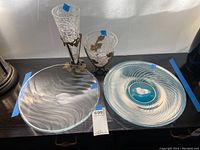 Four items: two crackled glass vases with metal stands and two decorative glass platters on a table under natural light.